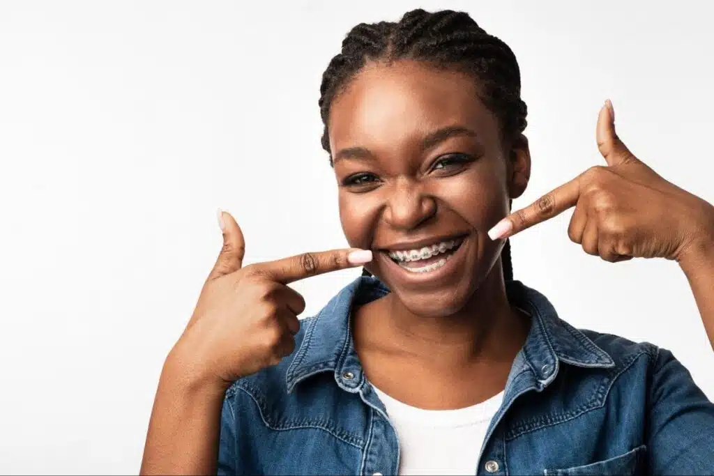 Young adult laughing with her braces, illustrating how long will you wear braces