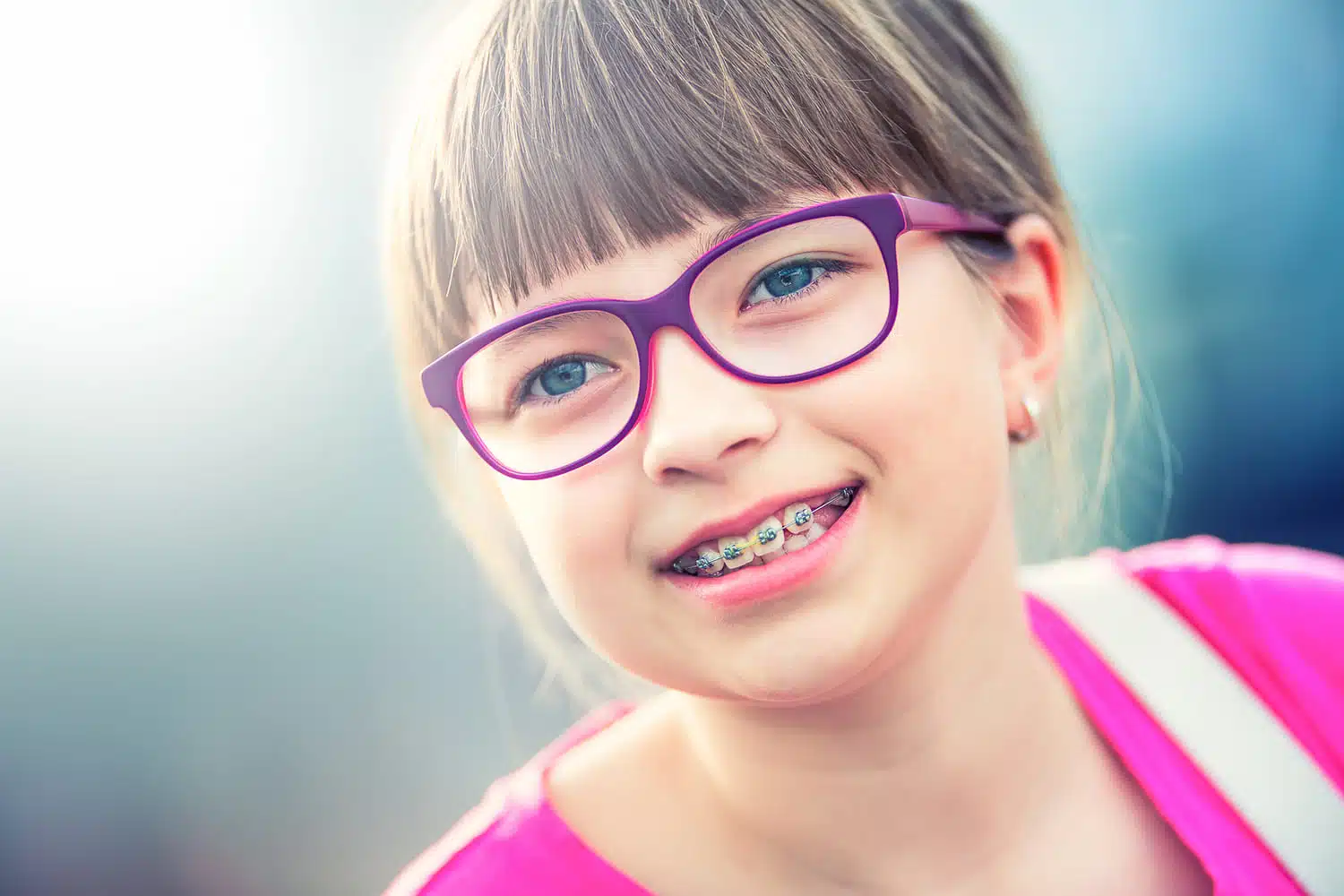 Girl smiling with braces, illustrating how long do you wear braces?