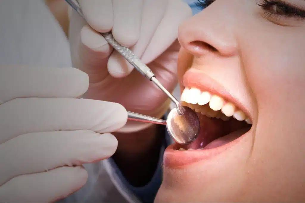Close-up of a dentist using a mirror and probe to examine a patient's teeth